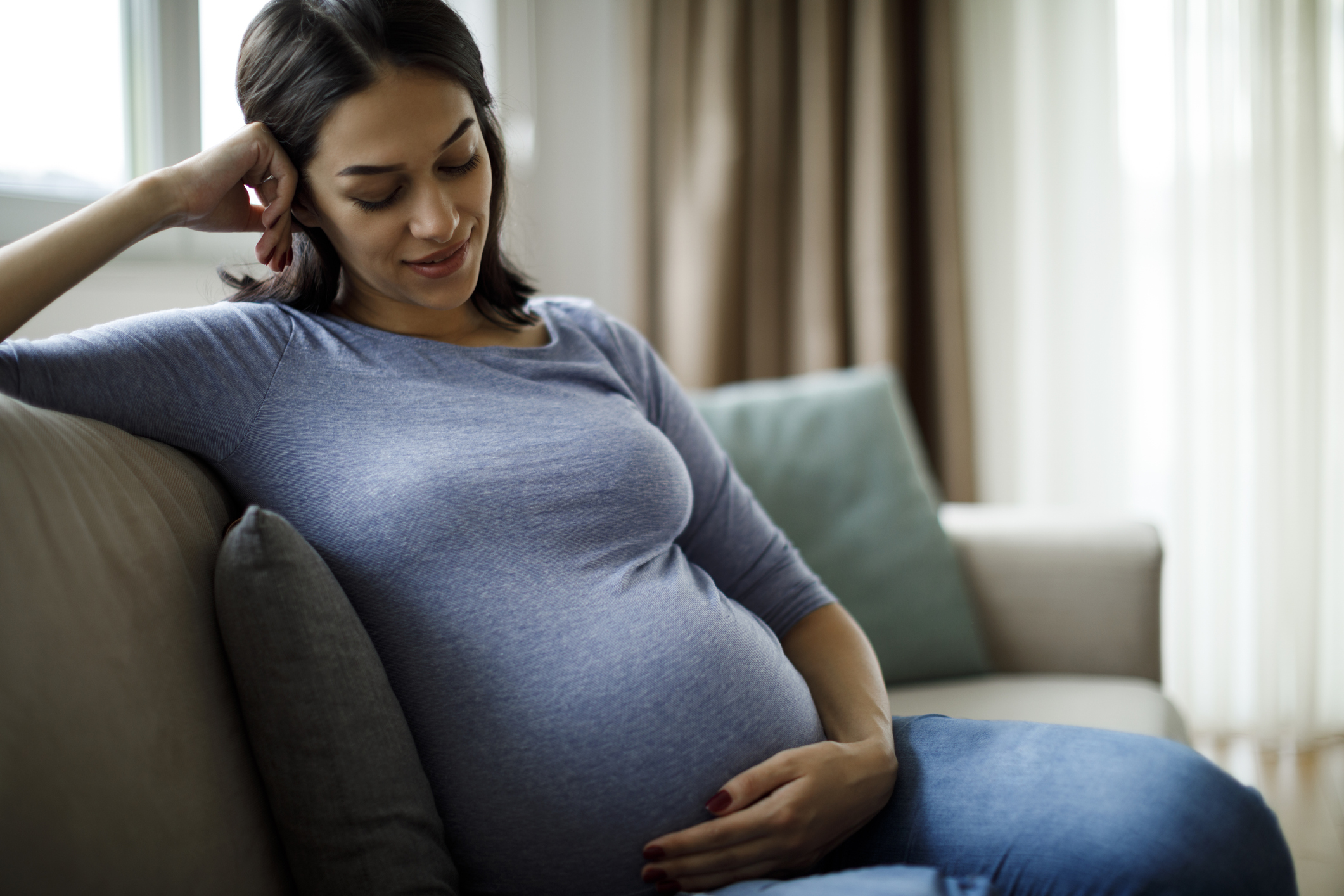 A pregnant woman relaxing on the couch at home